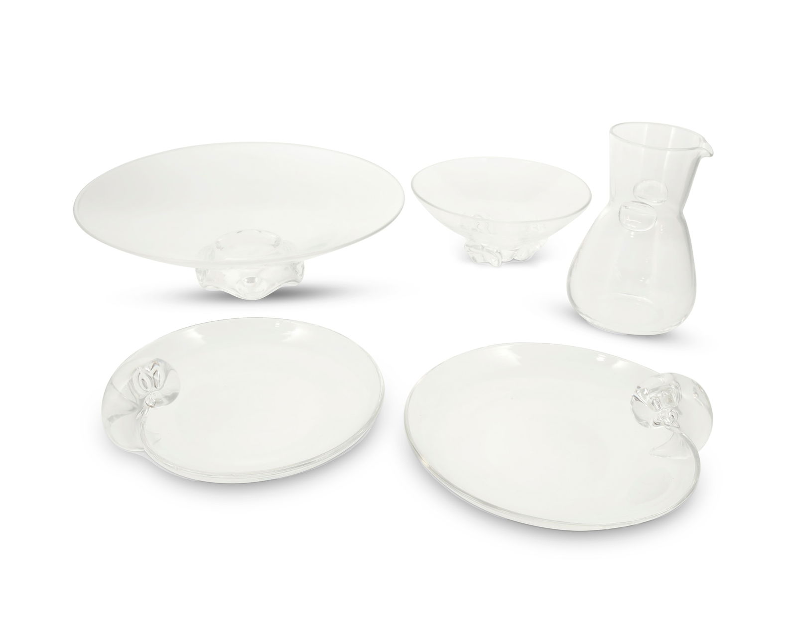 A group of Steuben glass table items: A group of Steuben glass table itemsLat 20th centuryEach with etched Steuben script markComprising a footed shallow bowl (3.875" H x 12.375" Dia.), two snail scroll handle dishes (3" H x 8.625" Dia.),