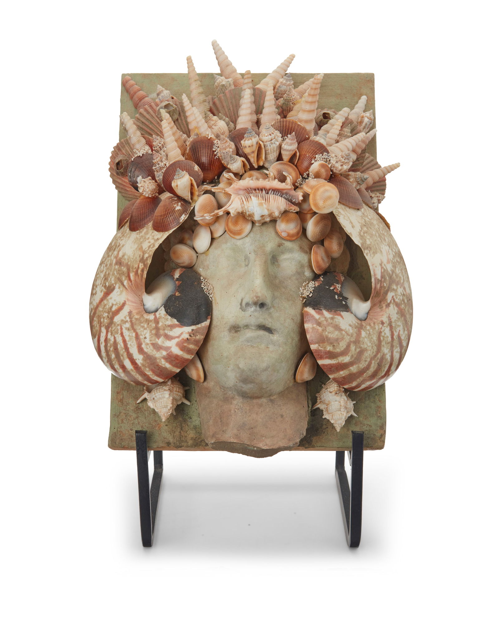 A Contemporary shell-encrusted plaque: A Contemporary shell-encrusted plaque20th centuryUnmarkedWith a ceramic face in relief on a rectangular backing, mounted with various seashells, set on an enameled metal display easel13.5" H x 9.75" W