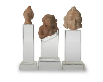 Three carved stone deity heads