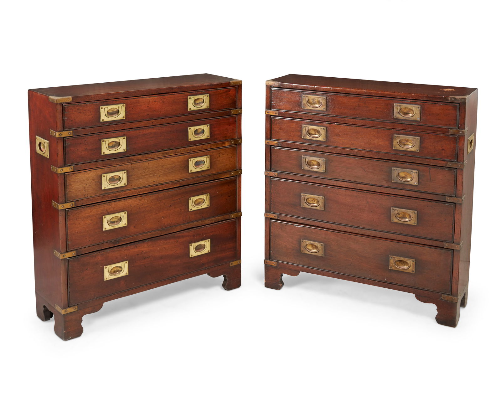 A pair of campaign-style brass-mounted dressers: A pair of campaign-style brass-mounted dressersEarly 20th centuryEach five-drawer dresser raised on bracket feet, with brass pulls, corner accents, and opposed handles, each with a gold-toned finish2