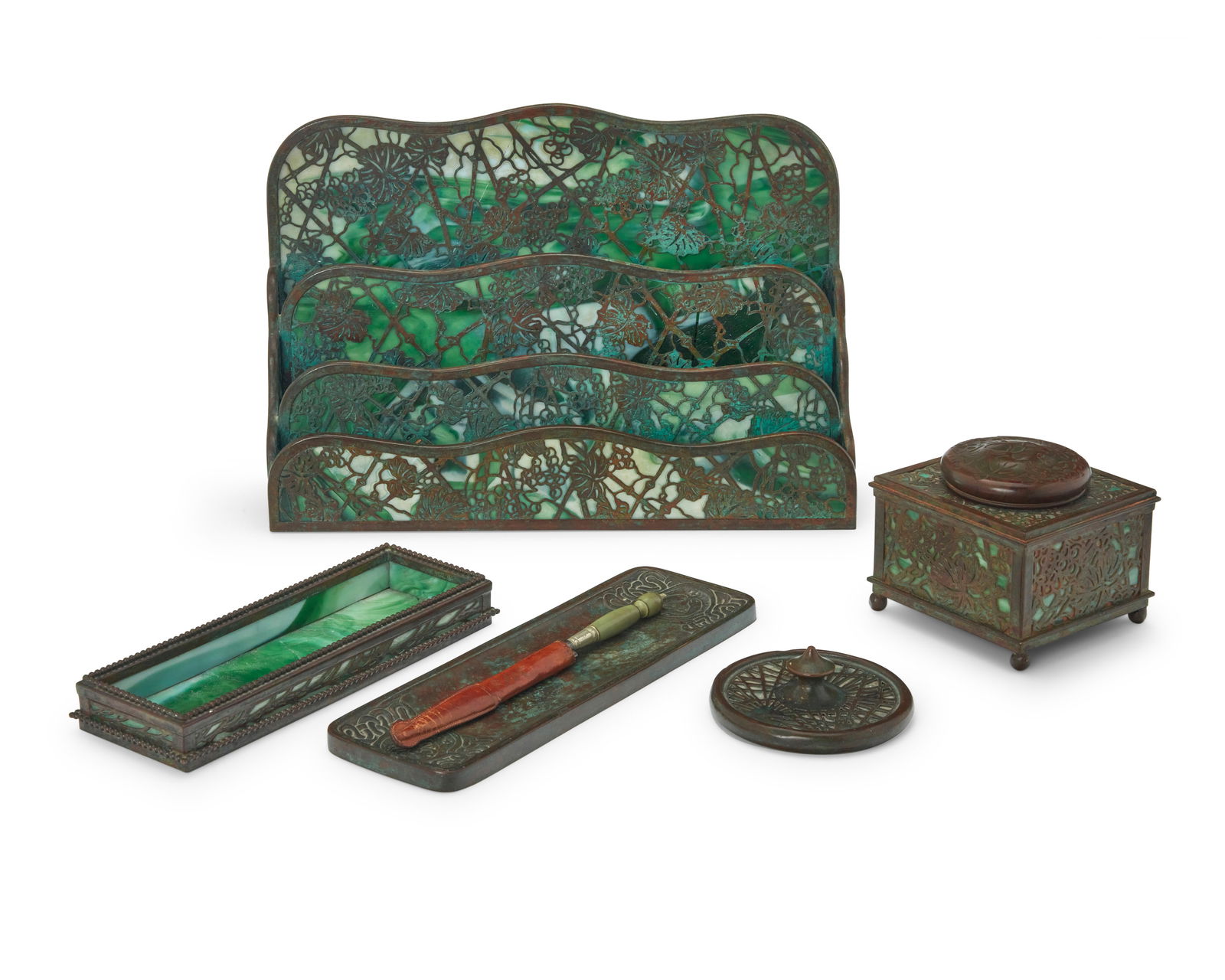 Five assembled Tiffany Studios desk accessories: Five assembled Tiffany Studios desk accessoriesEarly 20th centuryEach stamped: Tiffany Studios New YorkThe patinated bronze and green slag glass items, comprising a 'Grapevine' letter rack, no. 1007 (