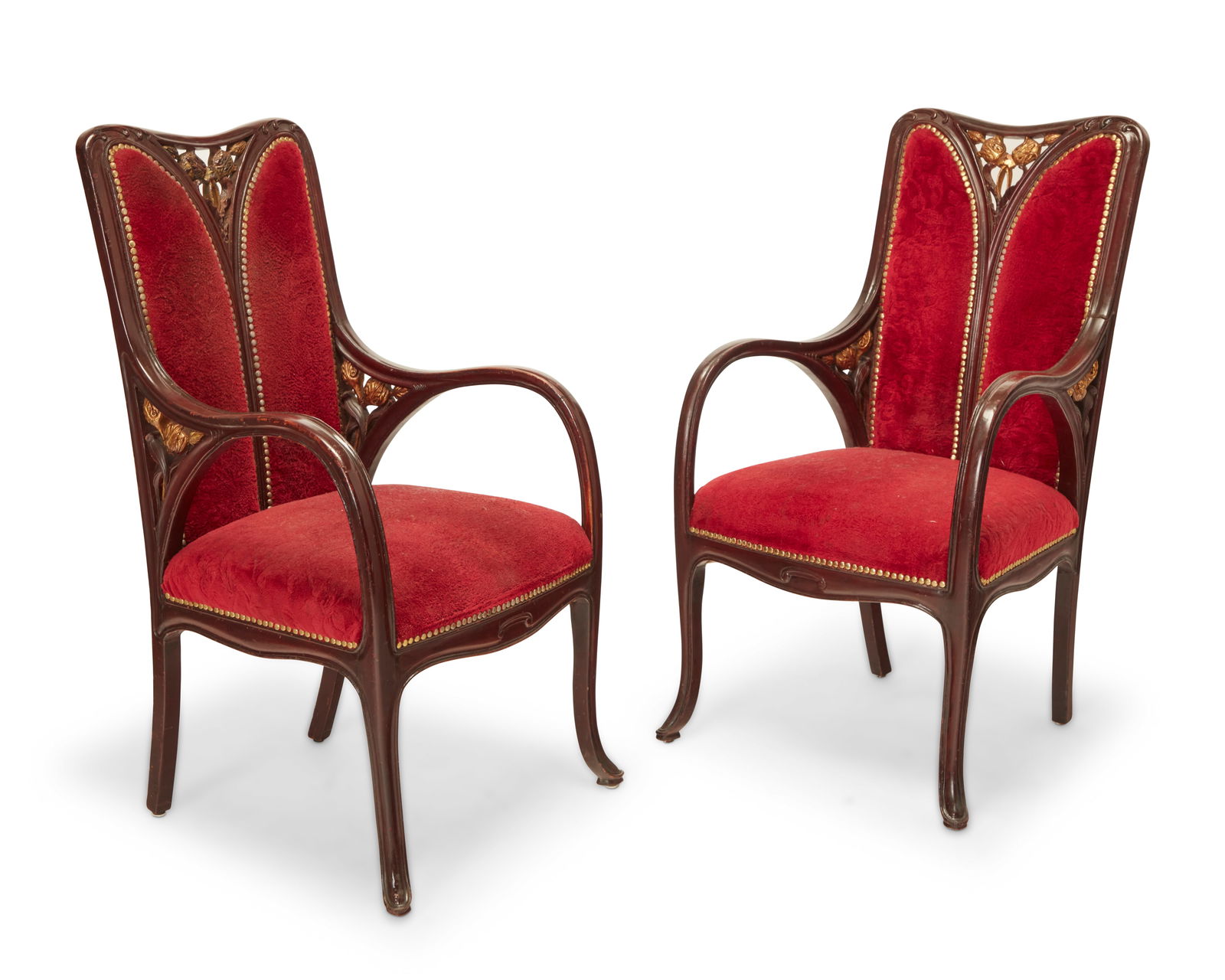 A pair of Art Nouveau carved wood armchairs: A pair of Art Nouveau carved wood armchairsEarly 20th centuryEach crest rail and armrest support with gilt foliate openwork accents, upholstered in high pile velvet fabric with brass tacking at seatba