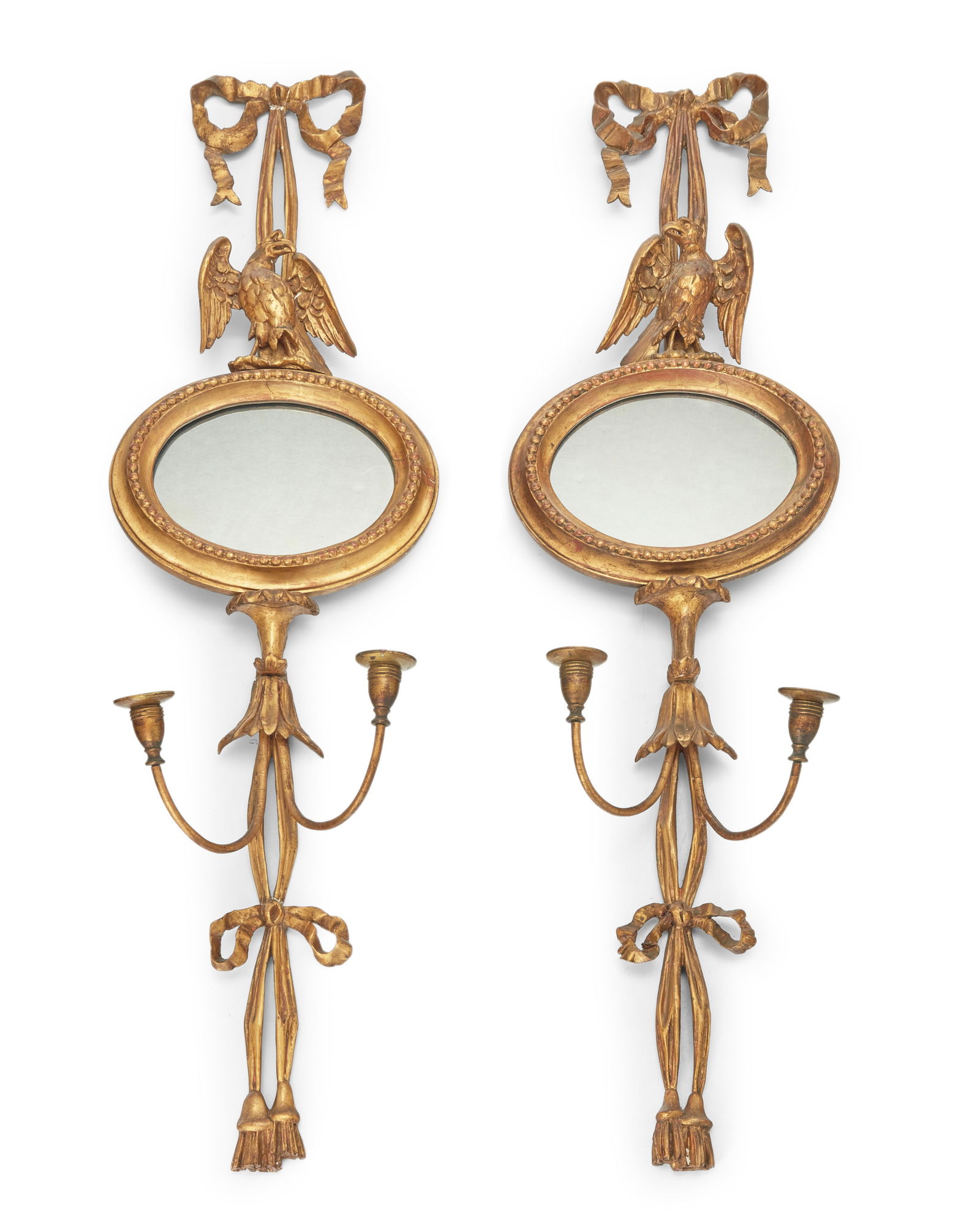 A pair of Regency style giltwood girandoles: A pair of Regency style giltwood girandoles 20th century Each with central mirror crested by an eagle, flanked by ribbons issuing two candle nozzles 2 pieces Each: 46.5" H x 12.25" W x 5.5" D 