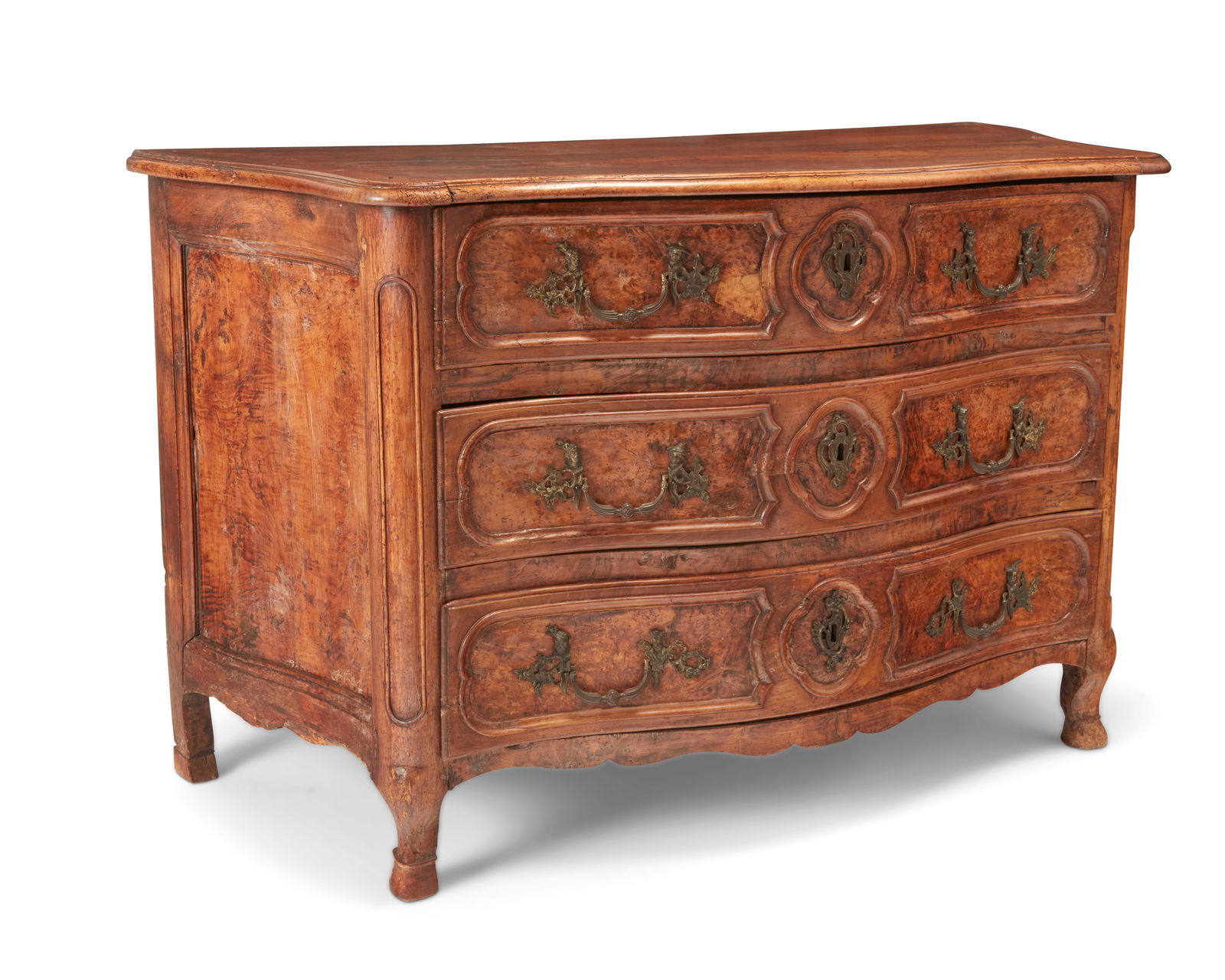 A Louis XV Provincial burl walnut commode: A Louis XV Provincial burl walnut commode18th centuryThe chest with three drawers, raised on front curved legs, featuring burlwood veneer to drawer fronts and side panels and figural brass pulls and l