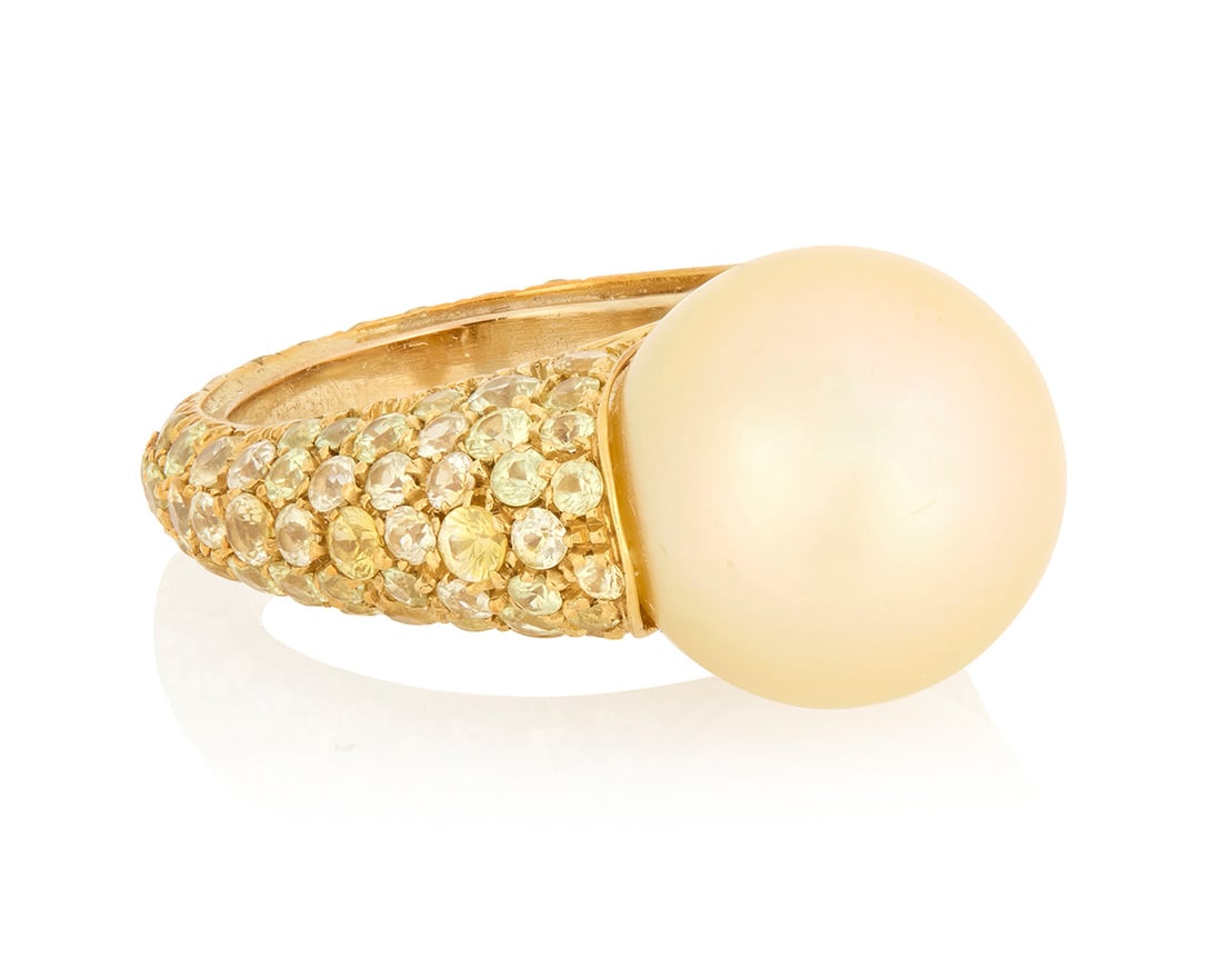 An 18K Gold, Cultured Pearl and Colored Sapphire: An 18K Gold, Cultured Pearl and Colored Sapphire Centering a golden cultured pearl measuring approximately 13.30 mm, accented by green and yellow sapphires Size: 5 1/2 with sizing spring 9.6 grams 