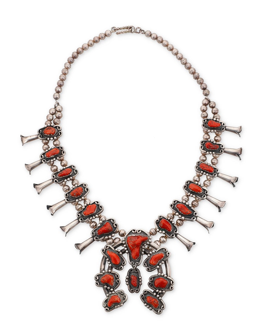 A Southwest sterling silver and coral squash blossom necklace: A Southwest sterling silver and coral squash blossom necklace Mid/late 20th century Unmarked A chunky double strand sterling silver squash blossom necklace with twelve elaborate set coral 'blossoms'