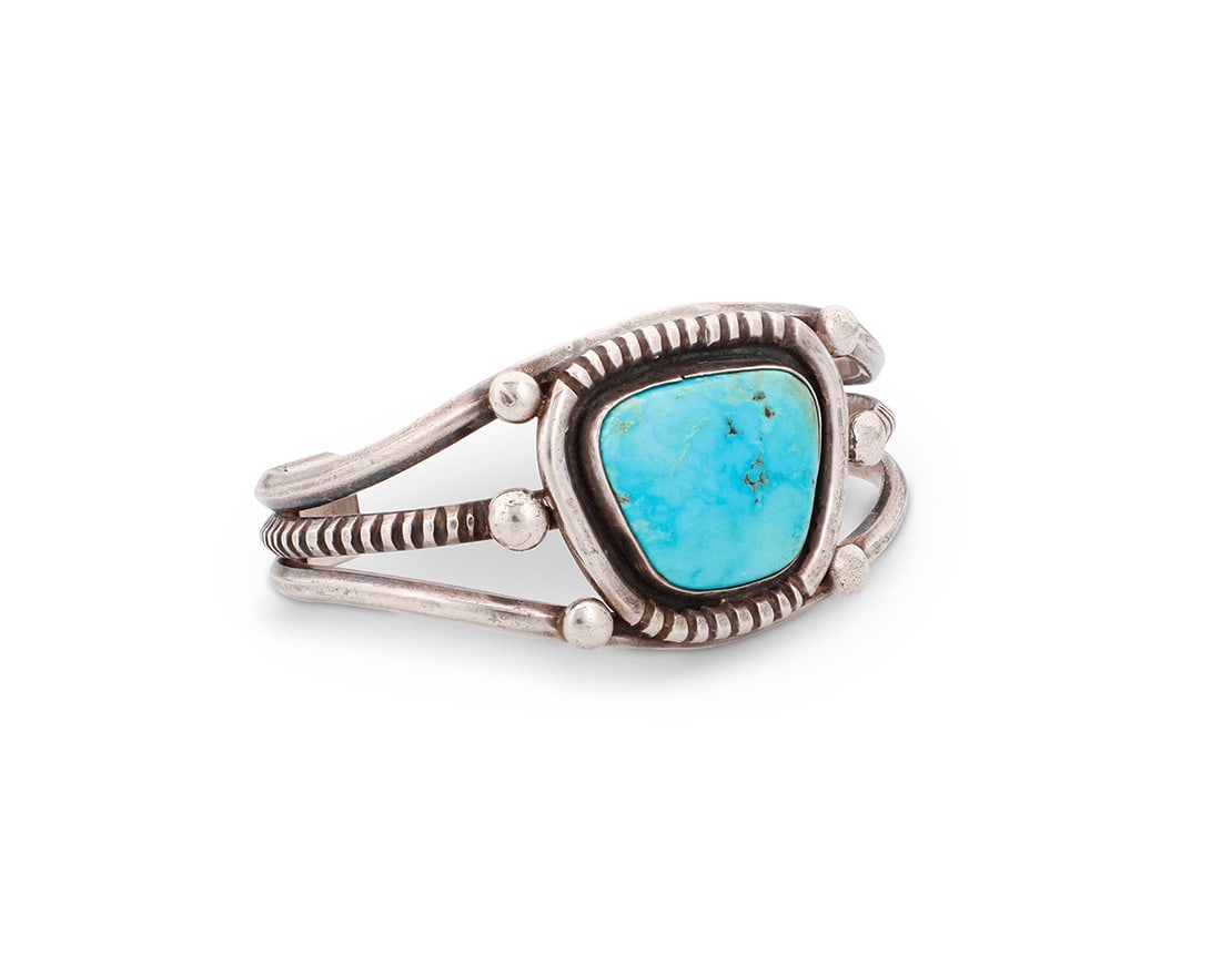 A Southwest sterling silver cuff bracelet: A Southwest sterling silver cuff bracelet Mid/late 20th century Unmarked A three-wire cuff with incised central wire and shaped central set trapezoid turquoise with incised edging and silver ball
