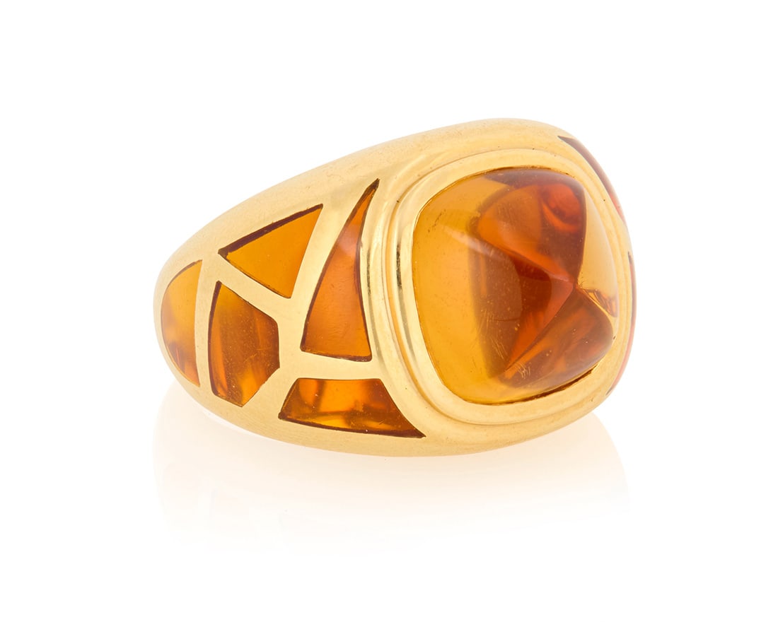 An 18K Gold and Citrine Ring: An 18K Gold and Citrine RingCentering a sugarloaf citrine accented by geometric gold openwork filled with orange accents, with French assay and makers marksSize: 7 3/413.1 grams grossProvenance:T