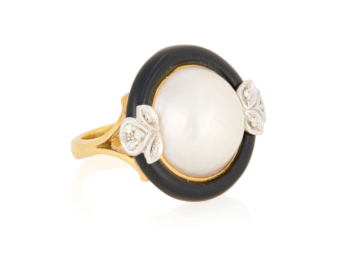 An 18K Gold, Mabe Pearl, Onyx and Diamond Ring: An 18K Gold, Mabe Pearl, Onyx and Diamond RingCentering a round mabe pearl accented by a carved circle of onyx, finished with two side embellishments set with round diamondsSize: 7 3/416.4 grams gross