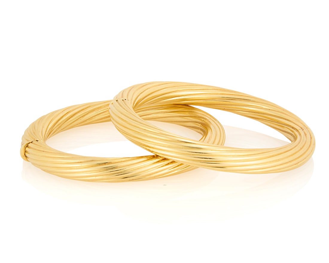 A pair of 18K Gold Bangles: A pair of 18K Gold BanglesOf a twisted high polish hinged design2 piecesMeasures: 6 3/4 in.108.2 gramsProvenance:The Estate of Joanna Carson