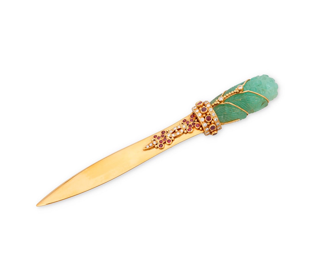An 18K Gold, Emerald, Ruby and Diamond Letter Opener: An 18K Gold, Emerald, Ruby and Diamond Letter OpenerFeaturing a shortened 18k gold blade topped by a foliate carved emerald, embellished by an ornate gold motif set with round rubies and diamondsMeasu