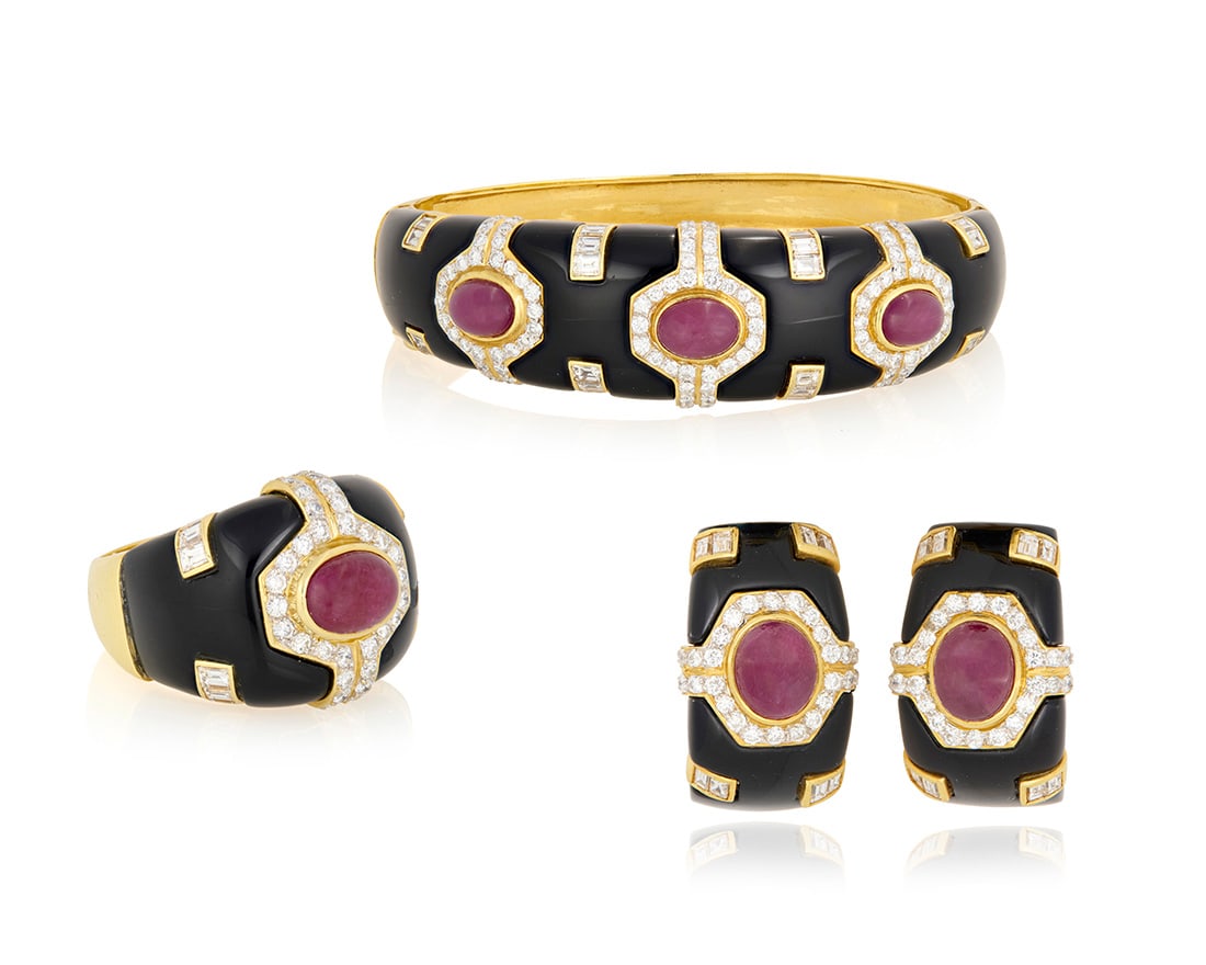 An 18K Gold, Onyx, Ruby and Diamond Suite: An 18K Gold, Onyx, Ruby and Diamond Suite Including a bangle, pair of earrings and ring all of a geometric design featuring onyx elements, oval ruby cabochons and accented by round and baguette