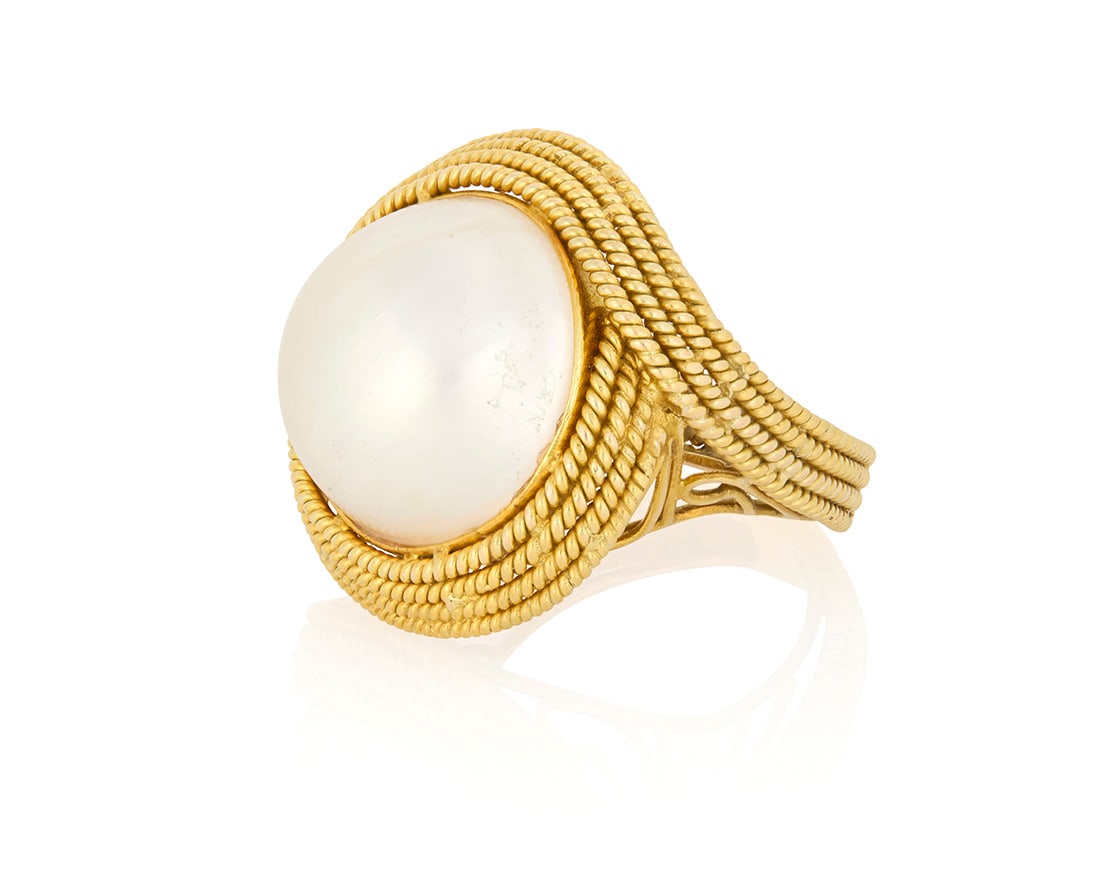 A 14K Gold and Mabe Pearl Ring: A 14K Gold and Mabe Pearl RingCentering a round mabe pearl accented by four rows of twisted gold rope motifsSize: 814.0 gramsProvenance:The Estate of Joanna Carson