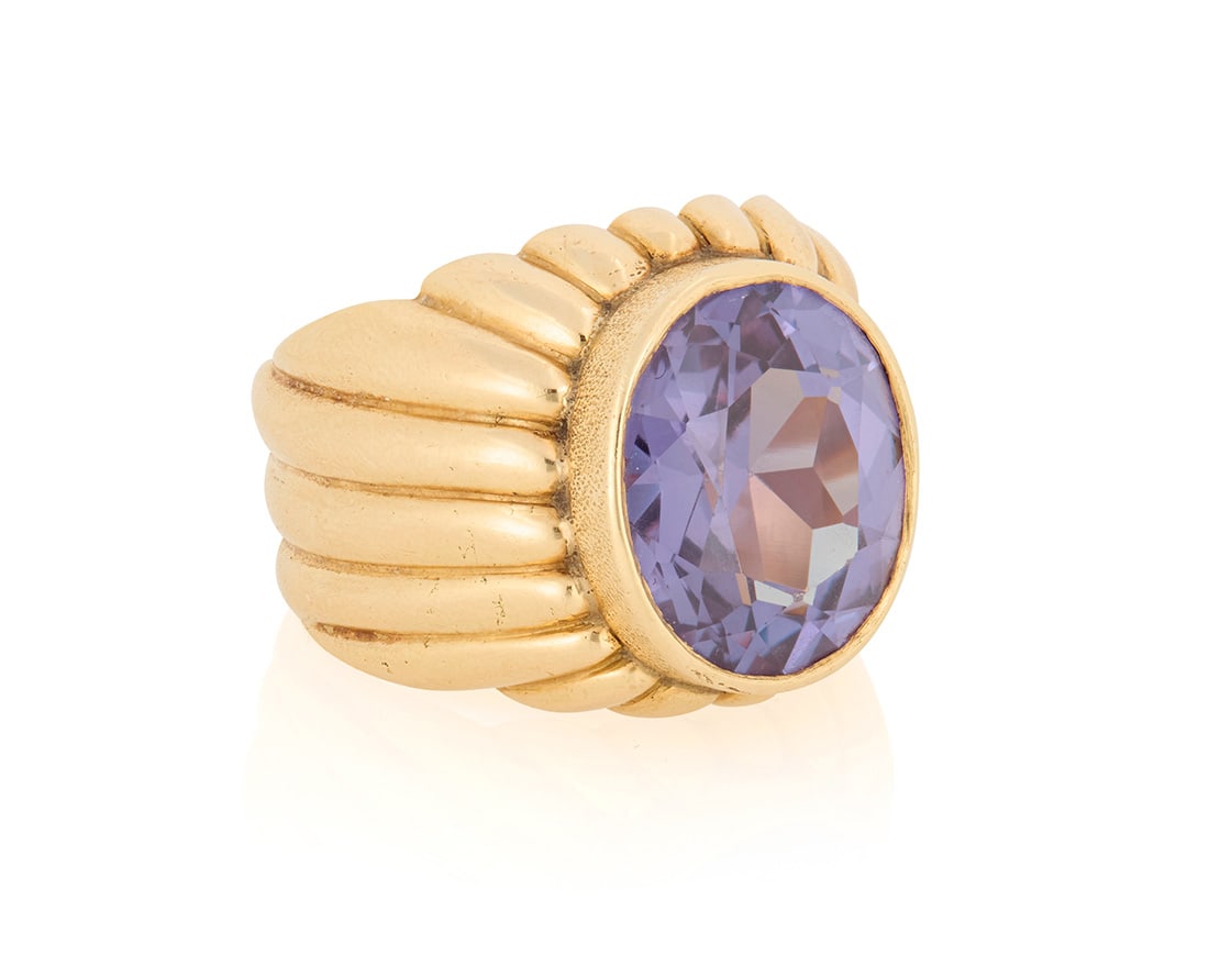 A 14K Gold and Synthetic Color-Change Sapphire Ring: A 14K Gold and Synthetic Color-Change Sapphire RingCentering an oval synthetic color-change sapphire weighing approximately 11.83 carats, finished with a fluted gold bandSize: 1017.6 grams grossProven