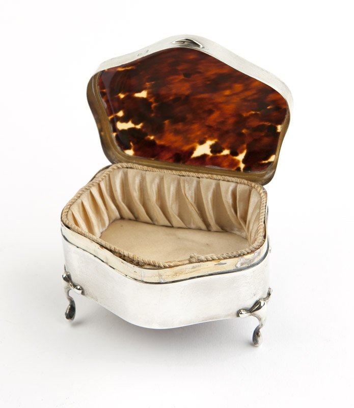 An Edwardian sterling silver pin box: 1914, Birmingham, maker's mark of Levi and Salaman, the serpentine form case with a hinged lid comprising a single panel of tortoiseshell, raised on four legs, hallmarked to case and lid, 2.25'' H x 3