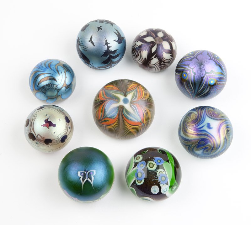 A group of paperweights, Orient & Flume, Lundberg: 1973-1977, each signed, iridescent with swirling designs, one with a forest scene, one with an interior fish design; 9 pcs, est: $400/600