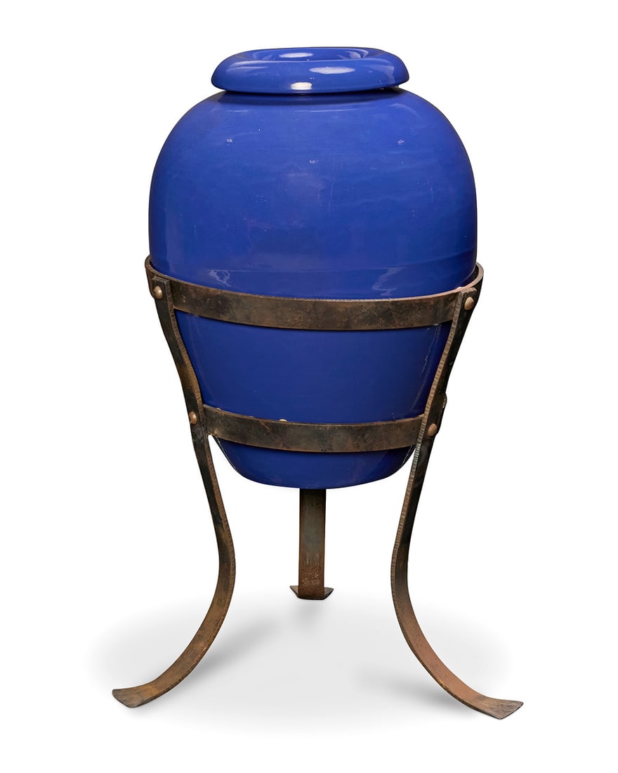 A Bauer blue glazed pottery oil jar on stand: A Bauer blue glazed pottery oil jar on stand Circa 1930s Unmarked Set in a wrought-iron tripod stand Jar: 21.25" H x 17" Dia.; Stand: 21.5" H x 21.25" W x 21.25" D