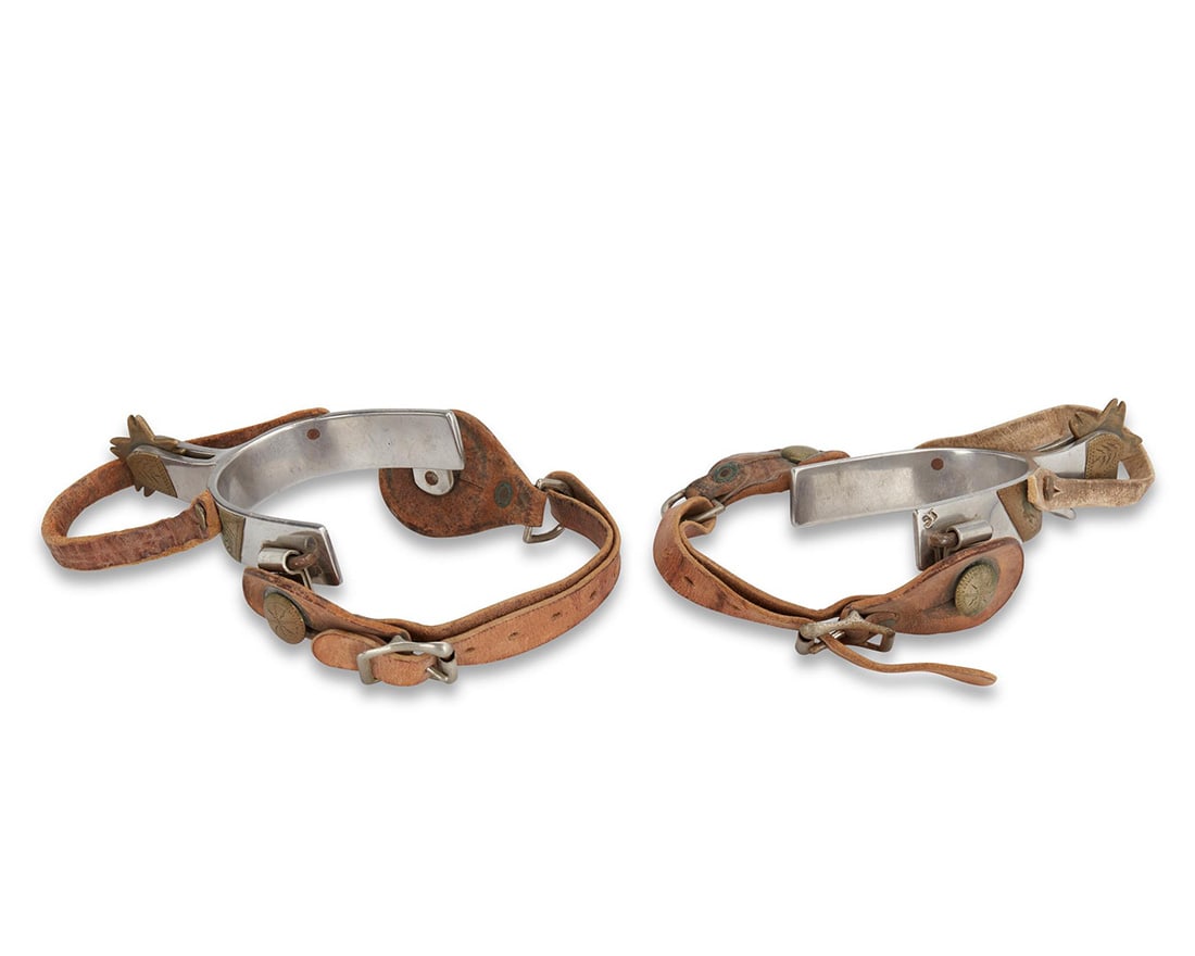 A pair of Crockett spurs: A pair of Crockett Western spurs20th centuryEach stamped: Crockett / StainlessThe stainless steel spurs with small five point star rowels and inset chased brass metal accents, each with two leather st