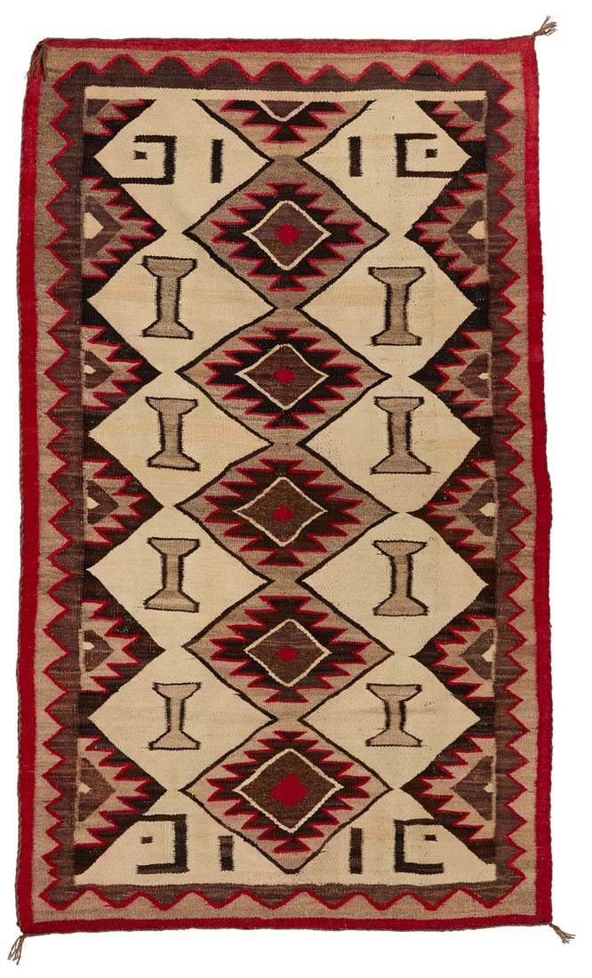 A Navajo regional rug: A Navajo regional rug Early 20th century, Dine Woven in red, tan, natural grey, and natural dark brown wool, with stacked serrated diamonds and I-forms within a sawtooth border 65.5" H x 38.5" W