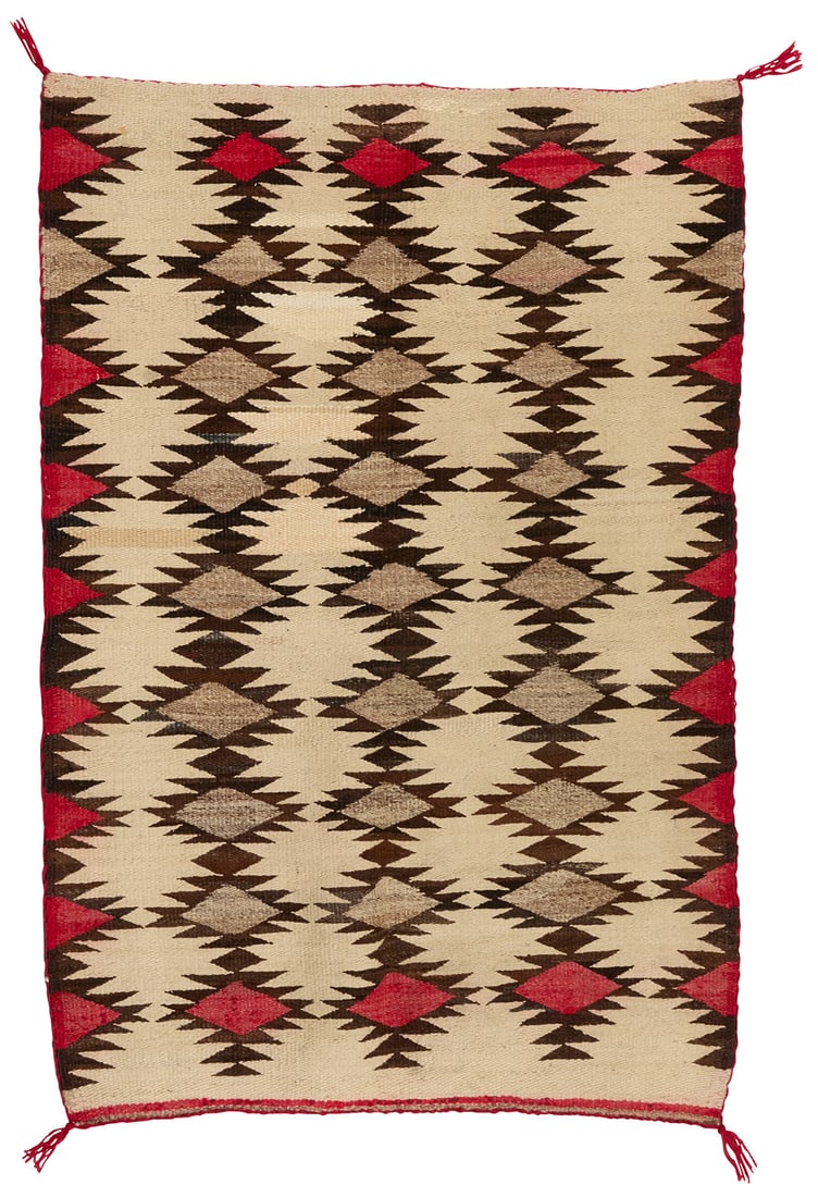 A Navajo regional rug: A Navajo regional rug Early 20th century, Dine Woven in red, dark brown, cream, and natural grey/brown wool, with four rows of stacked serrated diamonds 47" H x 32" W