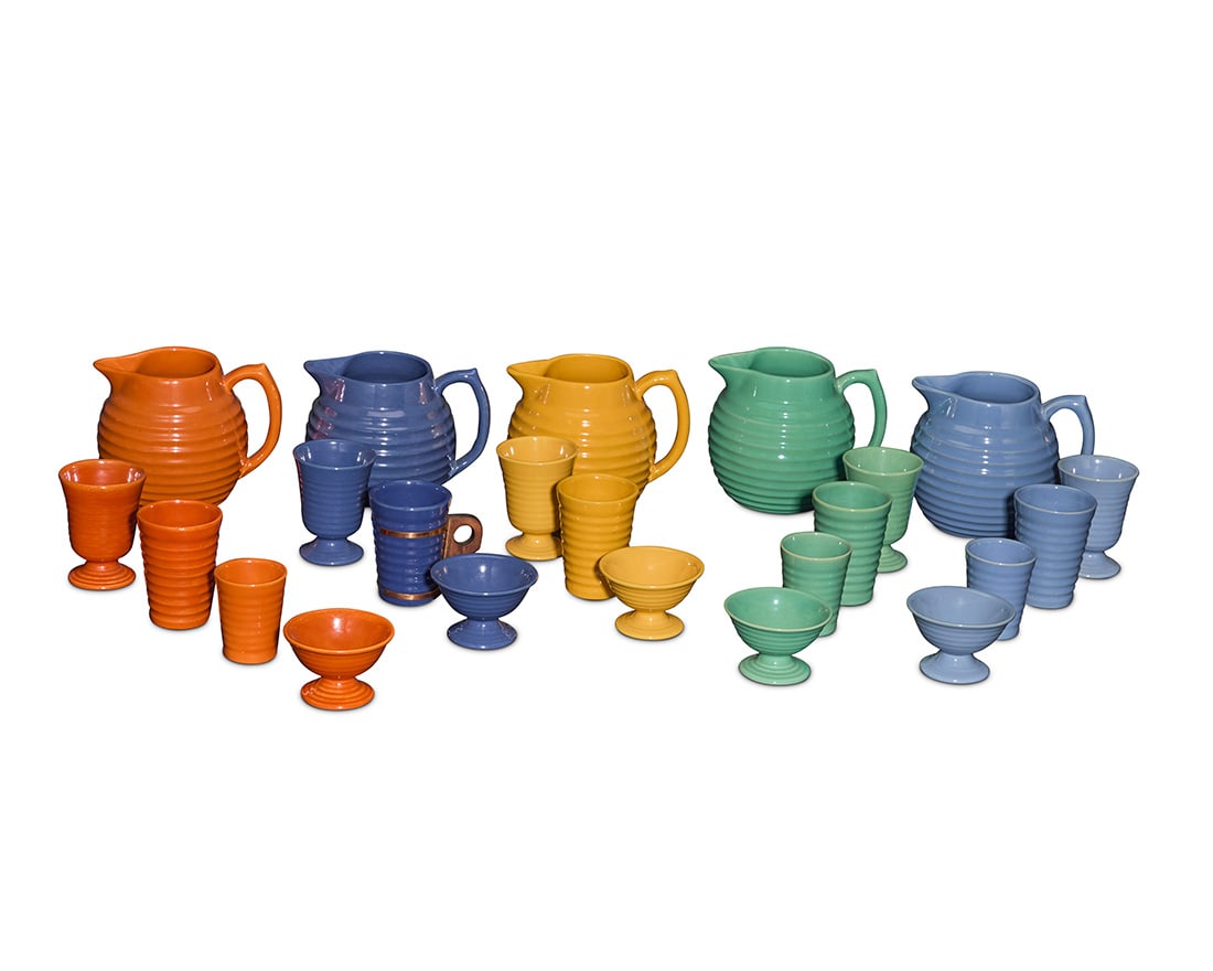 A group of Bauer glazed pottery ringware table items: A group of Bauer glazed pottery ringware table items Circa 1930s Comprising 5 taller cups (one with a copper holder and wood handle), 3 smaller cups, 5 footed cups, 5 footed bowls, and 5 pitchers,