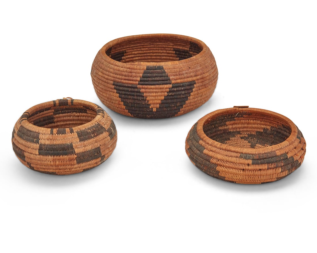 A group of diminutive Pomo baskets: A group of diminutive Pomo basketsEarly 20th century; Northern CaliforniaThree coiled low basketry bowls, the largest with three geometric stylized floral motifs, and the smaller bowls with stepped ra