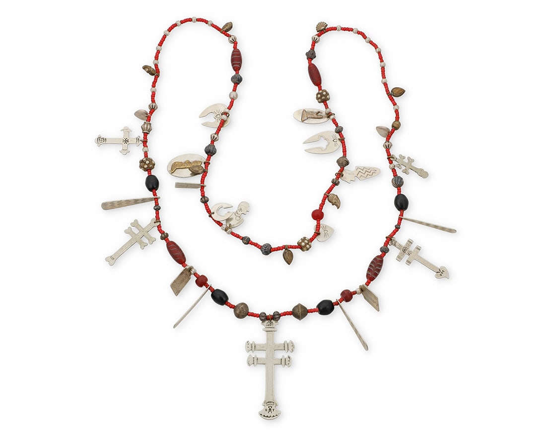 An Isleta Pueblo style trade bead necklace: An Isleta Pueblo style trade bead necklace Late 20th century Some elements stamped: GDT A long strand with multiple silver-toned stamped and incised metal elements including crosses, medallions,