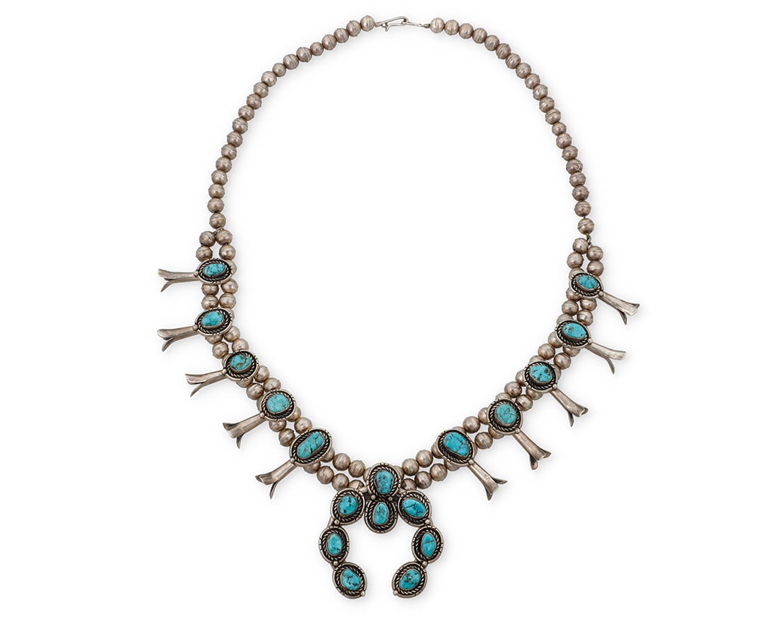 A Southwest sterling silver and turquoise squash blossom necklace: A Southwest sterling silver and turquoise squash blossom necklace Mid/late 20th century Unmarked A chunky double strand necklace with ten graduated set turquoise blossoms, suspending a large central