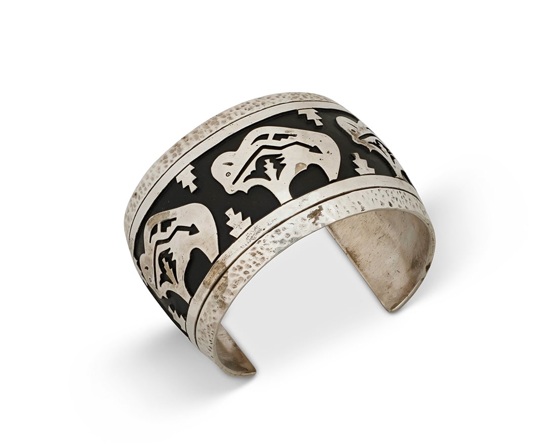 A large Tommy Singer Navajo sterling silver cuff bracelet: A large Tommy Singer Navajo sterling silver cuff bracelet Tommy Singer (1940-2014, Dine) Late 20th century Stamped: T Singer / Sterling A chunky silver pictorial cuff with heartline buffalo silver