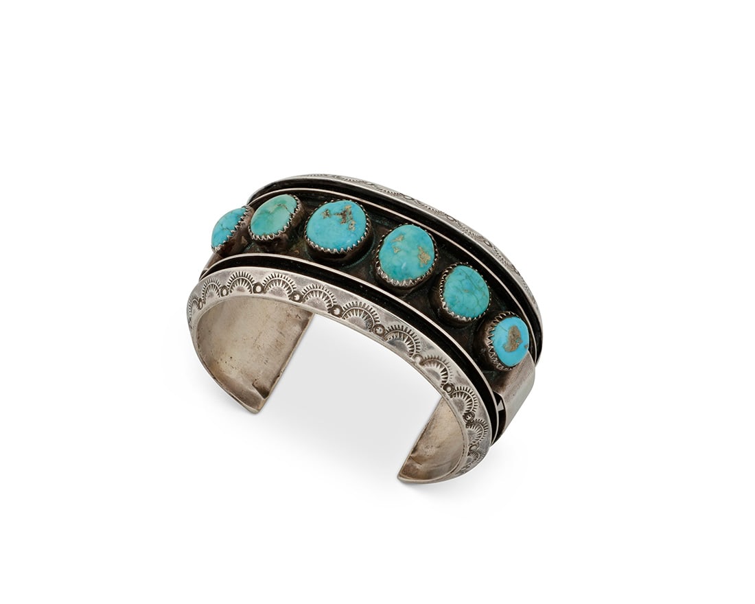 An Alice Sam Navajo silver and turquoise cuff bracelet: An Alice Sam Navajo silver and turquoise cuff bracelet Alice Sam (b. 20th century, Dine) Late 20th/early 21st century Stamped: Alice Sam A chunky cuff with six shadow set turquoise cabochons and