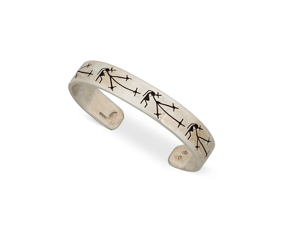A Victor Coochwytewa Hopi silver pictorial cuff bracelet: A Victor Coochwytewa Hopi silver pictorial cuff bracelet Victor Coochwytewa (1922-2011, Hopi) "Starblower: Brings Light into Darkness", circa 1985 Stamped with artist's mark of cloud with five rain