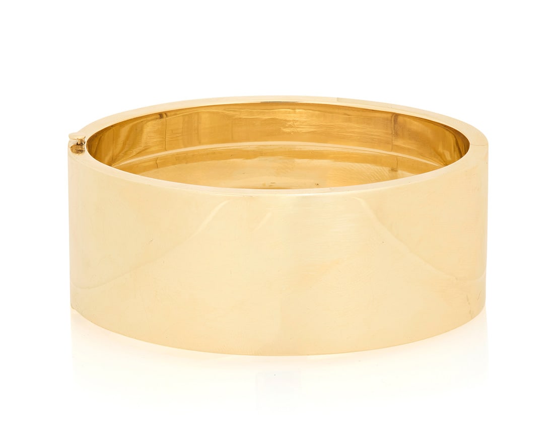 Tiffany & Co.: A 14K Gold Bangle: Tiffany & Co.: A 14K Gold Bangle Of a hinged, high polish design, signed Tiffany & Co. Inner circumference: 6 3/4 in., Width: 1 in. 51.1 grams gross