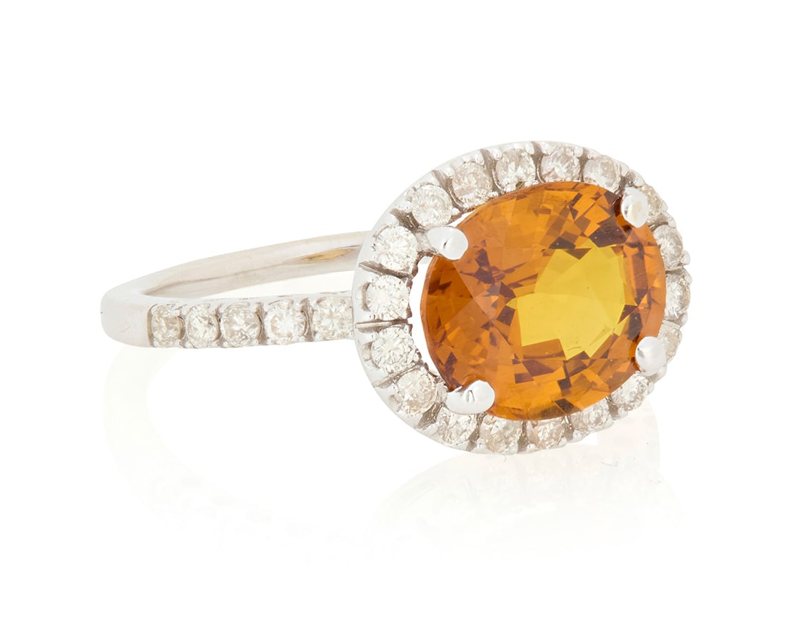 A 14K White Gold, Orange Sapphire and Diamond Ring: A 14K White Gold, Orange Sapphire and Diamond RingCentering an oval orange sapphire weighing approximately 3.57 carats, encircled by round diamondsSize: 6 3/43.5 grams