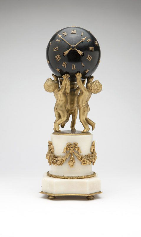 A Louis XVI style gilt bronze & white marble clock: Late 19th / early 20th century, the Roman numerals and arrow-form hands applied to a black-painted sphere adorned with stars, held aloft by three inward-facing cherubs atop a column encircled with a f