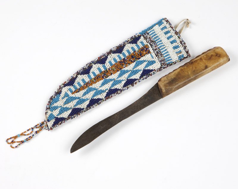 A Sioux beaded hide knife sheath and knife: Late 19th / early 20th century, the sheath beaded to one side with a geometric design in white, light blue, and dark blue with ''crazy beading'' to edges, suspending two beaded loops, the sheath 10''