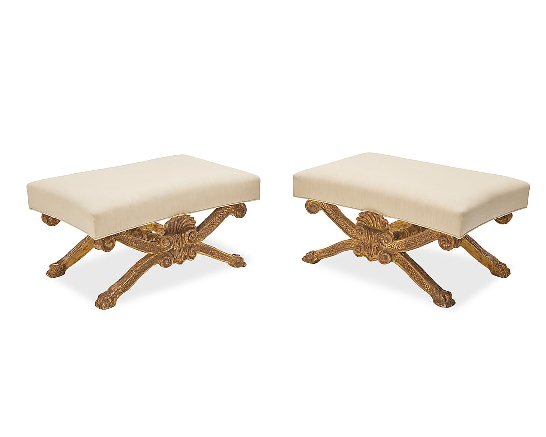 A pair of George II style giltwood stools: A pair of George II style giltwood stools 20th century, after William Kent The upholstered seats each on X-form supports joined by a turned stretcher, carved with scrolled ends and paw feet 2 pieces E