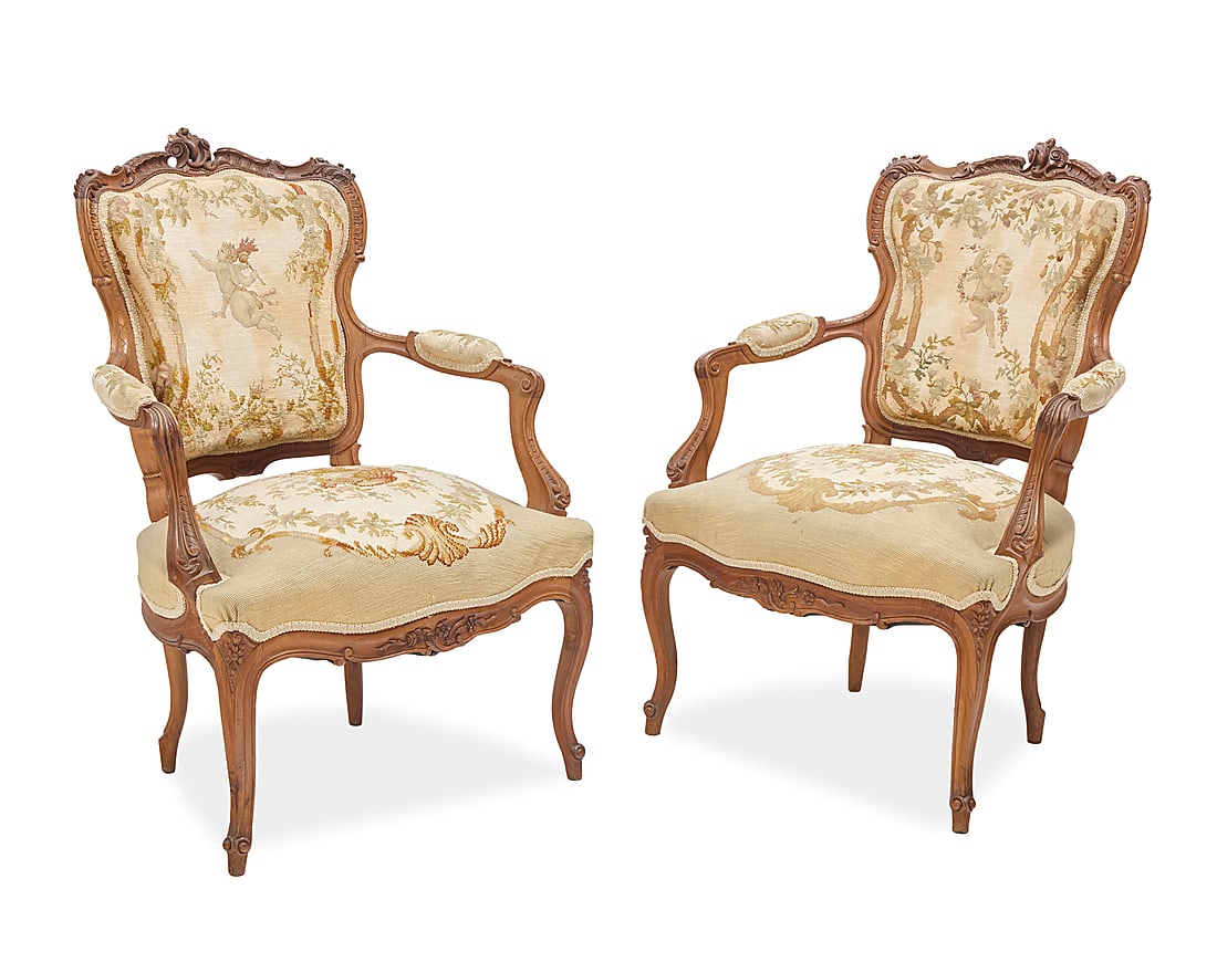 A pair of Louis XV style fauteuils: A pair of Louis XV style fauteuils Early 20th century Each wood frame carved with acanthus leaves, with needlepoint upholstery, the seat backs depicting putti in a floral framework and the seats a sus