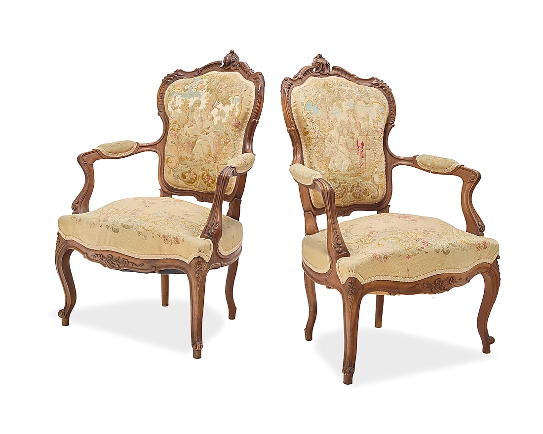 A pair of Louis XV style fauteuils: A pair of Louis XV style fauteuils Early 20th century Each wood frame carved with acanthus leaves, with needlepoint upholstery, the seat backs depicting couples in a landscape, the seats with flowers 