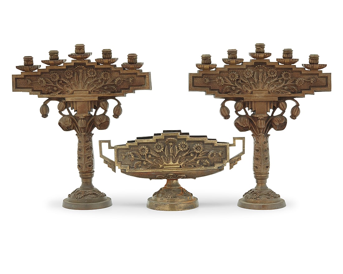 An Art Deco gilt bronze three piece garniture: An Art Deco gilt bronze three piece garniture Early 20th century Comprising a pair of five-light candelabra and a footed center bowl with metal liner, each depicting floral motifs 3 pieces Each candel