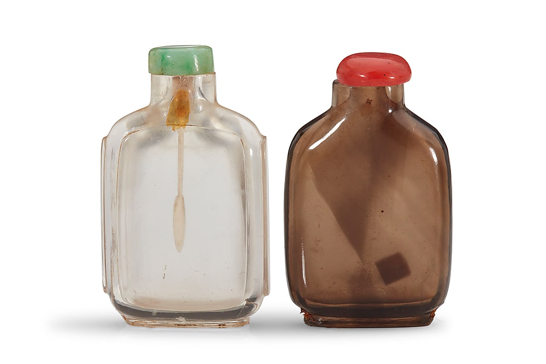 Two Chinese rock crystal snuff bottles: Two Chinese rock crystal snuff bottles 19th/20th century Comprising one clear and one smoky quartz 2 pieces Clear: 3" H x 1.75" W x 0.75" D; Smoky: 2.875" H x 1.875" W x 0.75" D