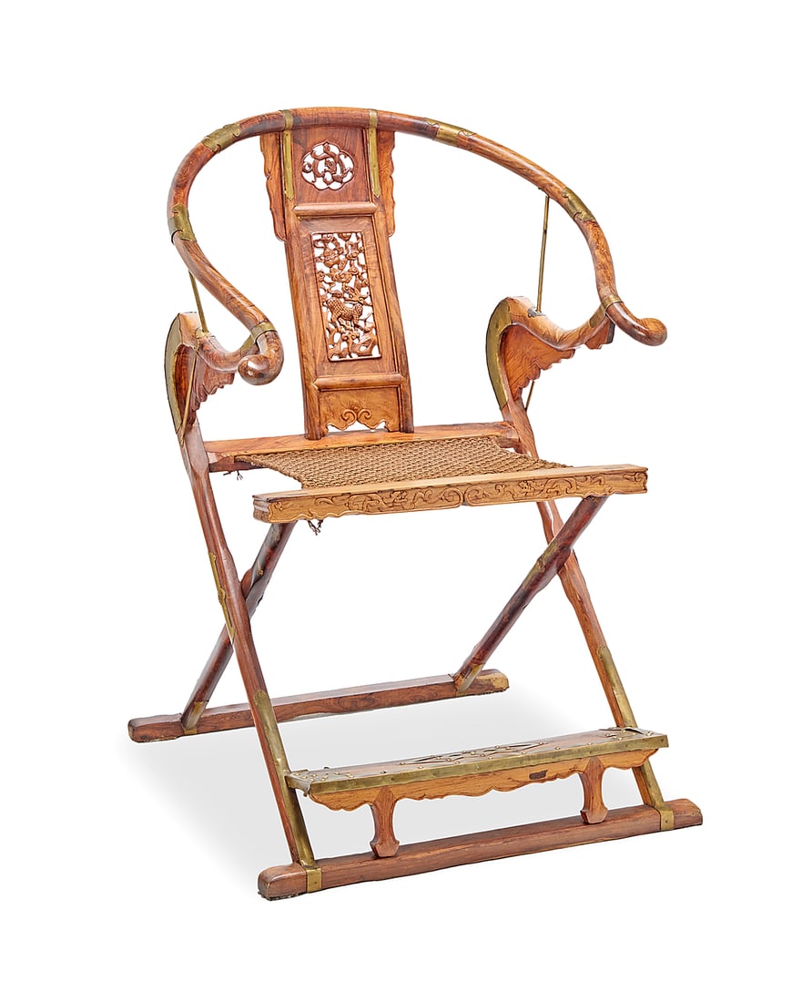 A Chinese elmwood folding chair: A Chinese elmwood folding chair 20th century With horseshoe crest rail and carved wood splat depicting a chilong figure among clouds, above a folding X-frame with corded seat and footrest, with brass 