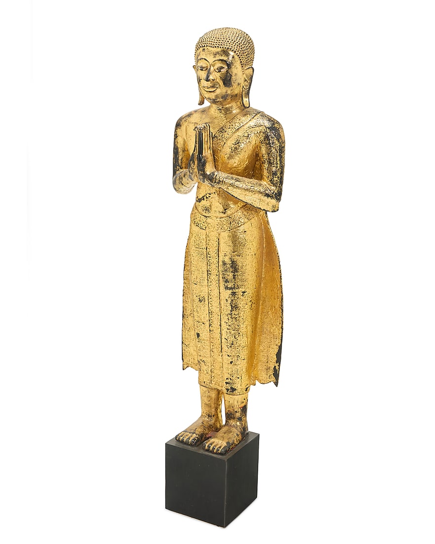 A Southeast Asian gilt metal standing Buddha: A Southeast Asian gilt metal standing Buddha Likely Thai, 19th/20th century Painted and gilt, with hands in Wai position, mounted on a wood plinth Figure: 49" H x 14.5" W x 11" D; Overall: 58" H Prove