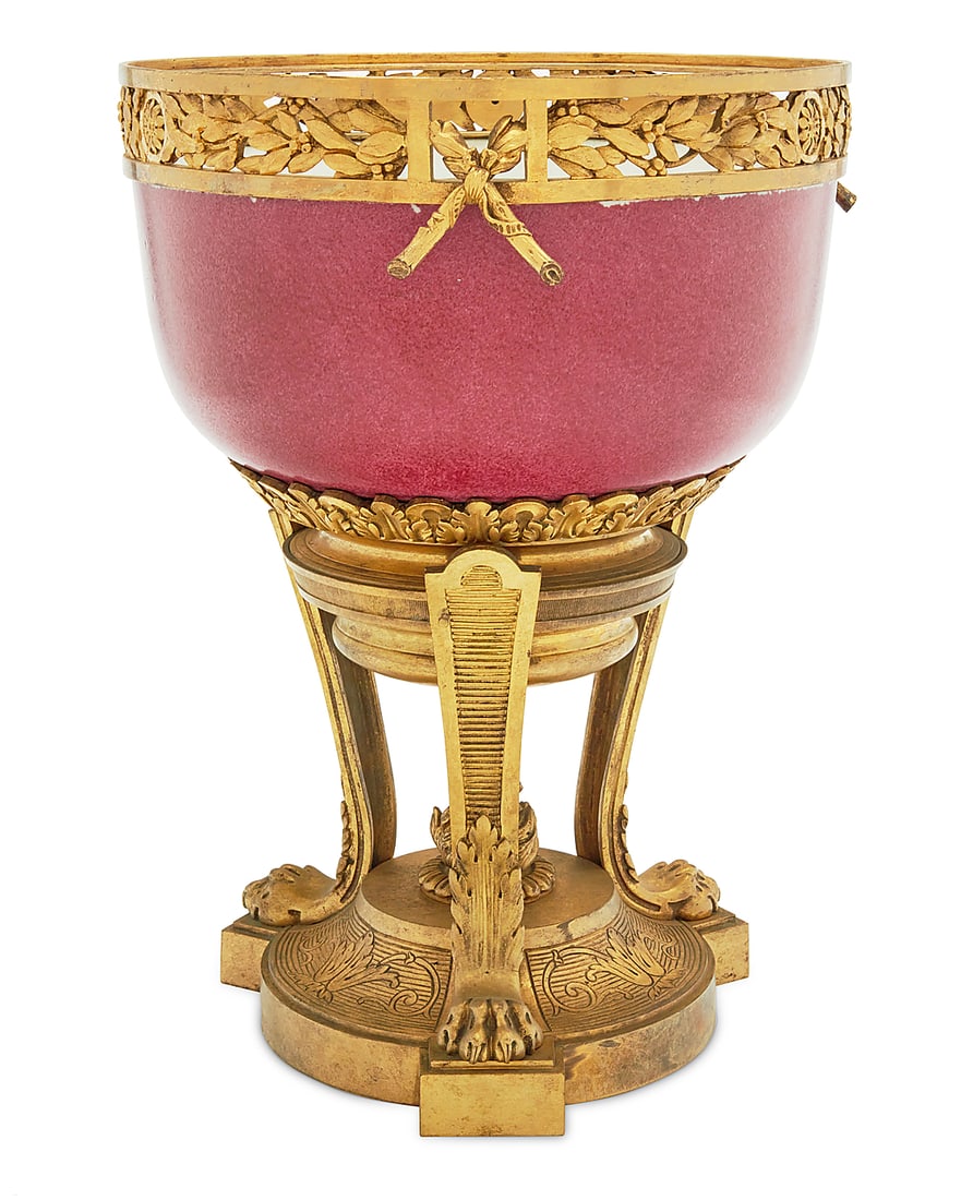A French gilt bronze and porcelain centerpiece: A French gilt bronze and porcelain centerpiece 19th century With pierced laurel wreath rim above a raspberry glazed porcelain bowl, raised on a tripod base with lion paw feet and central flame finial