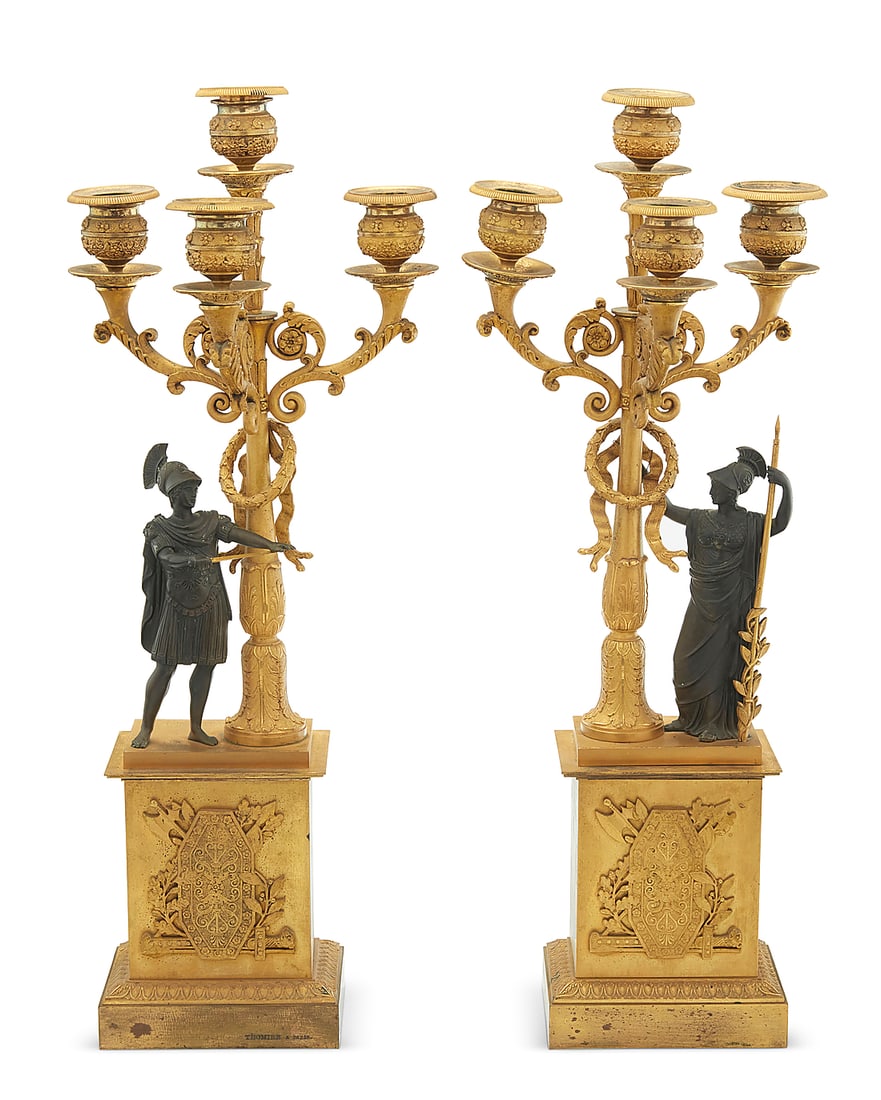 A pair of Empire parcel gilt bronze figural candelabra: A pair of Empire parcel gilt bronze figural candelabra Pierre-Philippe Thomire (1751-1843), early 19th century One impressed: THOMIRE A PARIS Each with patinated Roman figure beside a standard with la