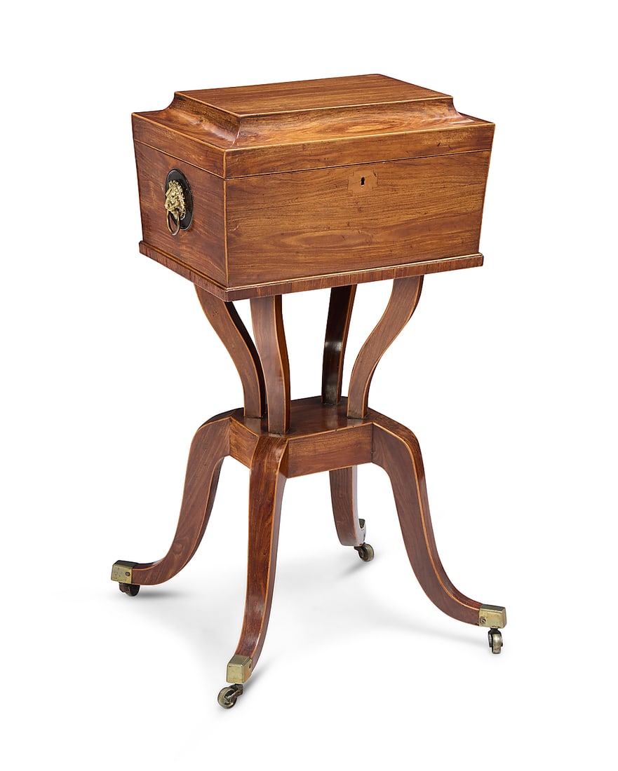 A Regency rosewood teapoy: Y A Regency rosewood teapoy Early 19th century The edges with inlaid trim, the locking lid opening to reveal four wood tea caddies centered by a tin lidded compartment, the casket mounted with