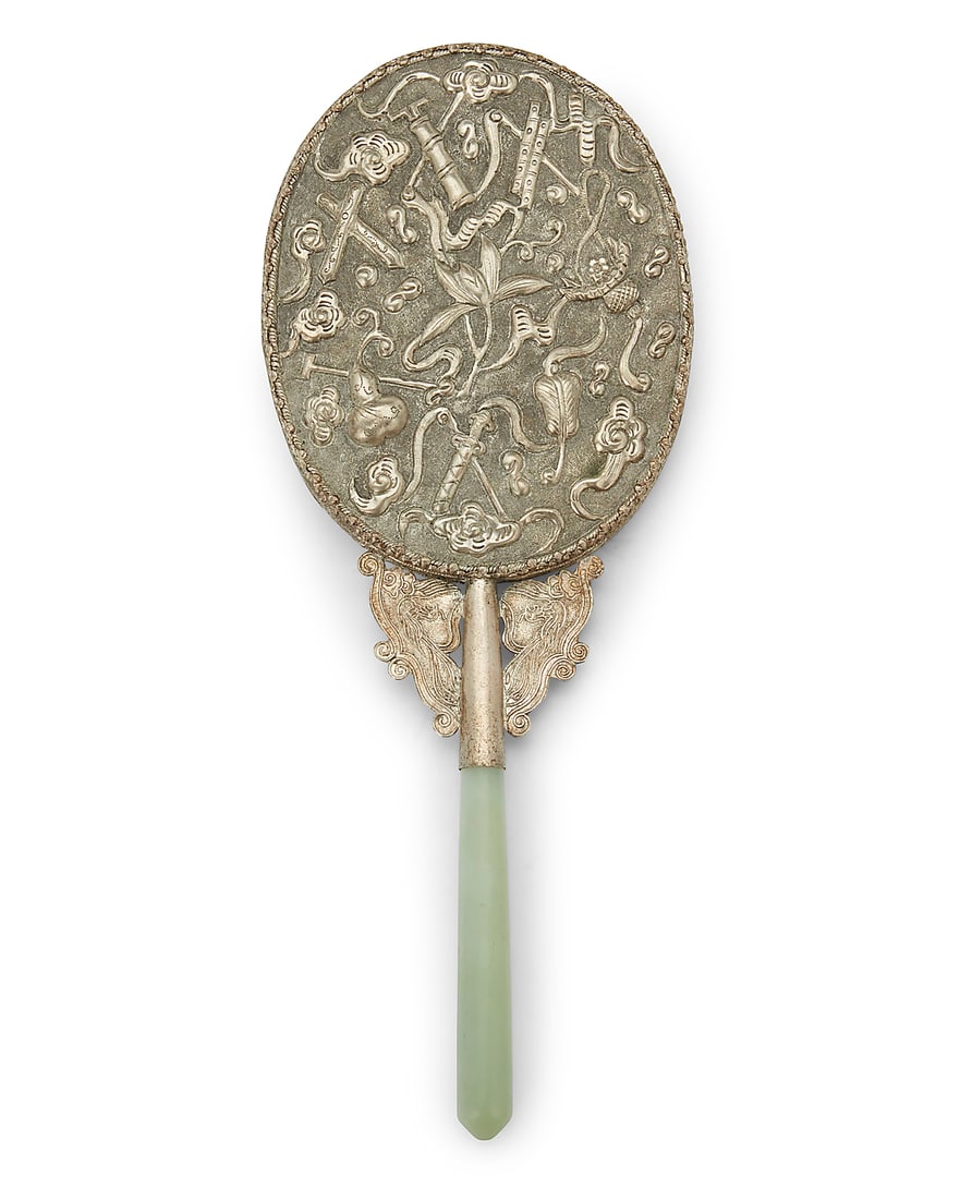 A Chinese silver plated mirror with jade handle: A Chinese silver plated mirror with jade handle Circa 1900s or later The repousse backing depicting 'One Hundred Antiques' motifs 10" H x 4" W x 0.75" D