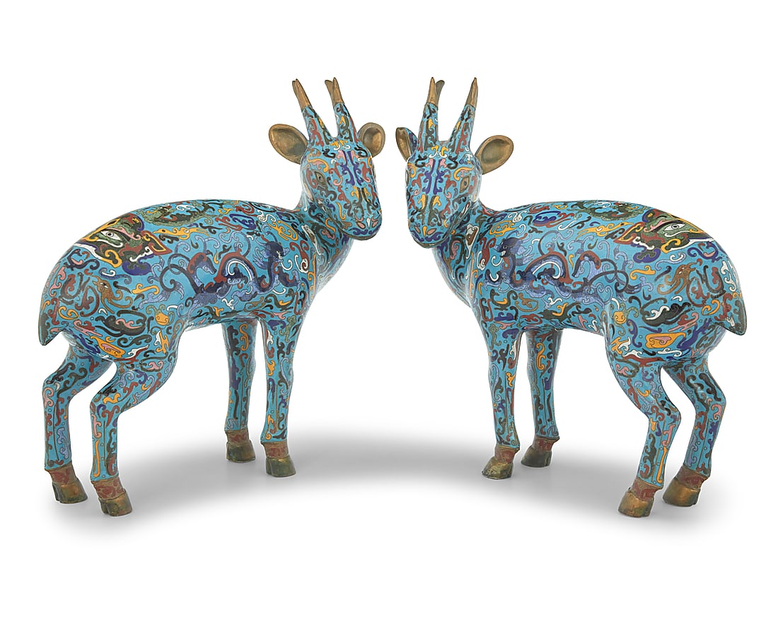 A pair of Chinese cloisonne models of deer: A pair of Chinese cloisonne models of deer Late 19th/20th century Each deer cast in bronze, with brass and polychrome enamel depicting dragons, taotie masks, and filigree on a Jingtai blue ground 2