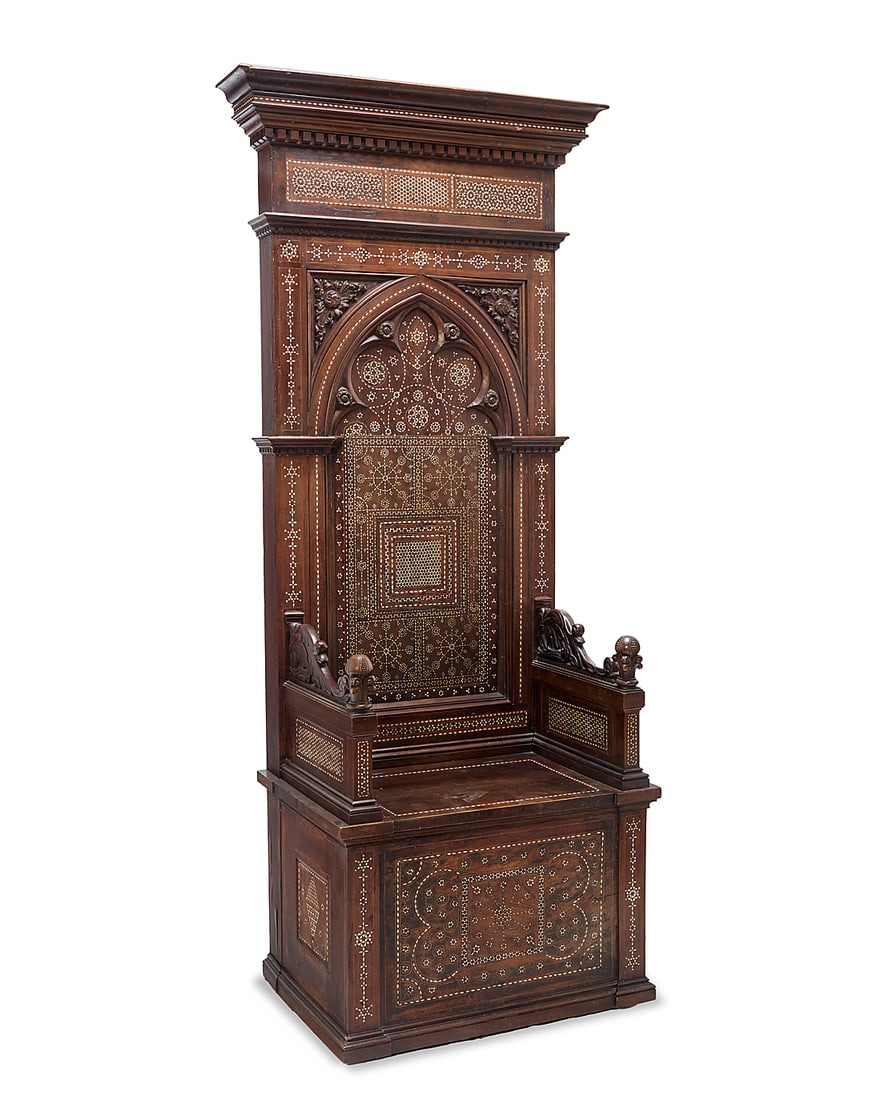 A Gothic Revival bone inlaid mixed wood throne chair: A Gothic Revival bone inlaid mixed wood throne chair 19th century With denticulated pediment above an archway seatback carved with foliate motifs and inlaid with bone, forming geometric designs, the s