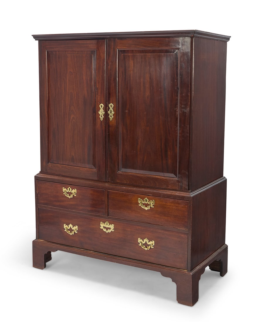 A George III mahogany linen press: A George III mahogany linen press Early 19th century The upper compartment with locking cabinet doors opening to reveal a later fabric-lined interior with single shelf and cut-outs at back for electri