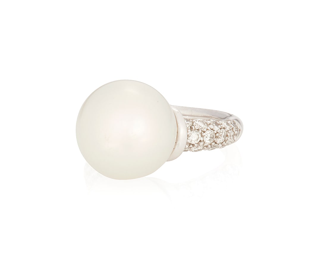 An 18K White Gold, Cultured Pearl and Diamond Ring: An 18K White Gold, Cultured Pearl and Diamond Ring Centering a large cultured pearl measuring approximately 12.75 mm, accented by round diamonds Size: 4 1/2 8.5 grams gross